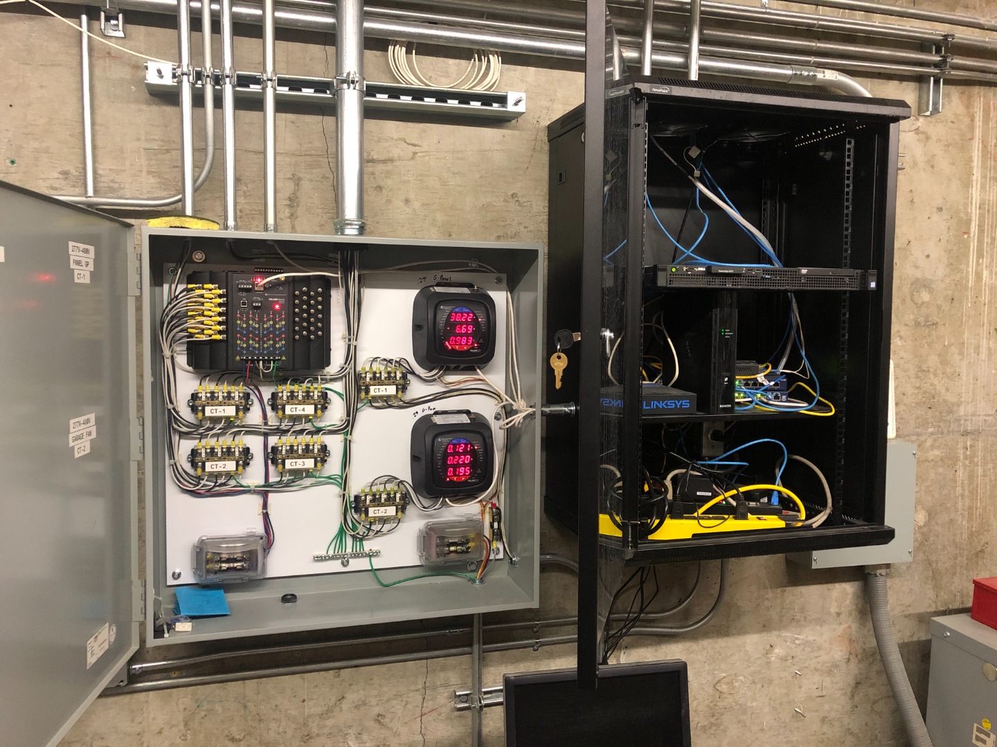 Full view of the smart metering panel alongside the Linksys network rack — the SCADA and communications infrastructure