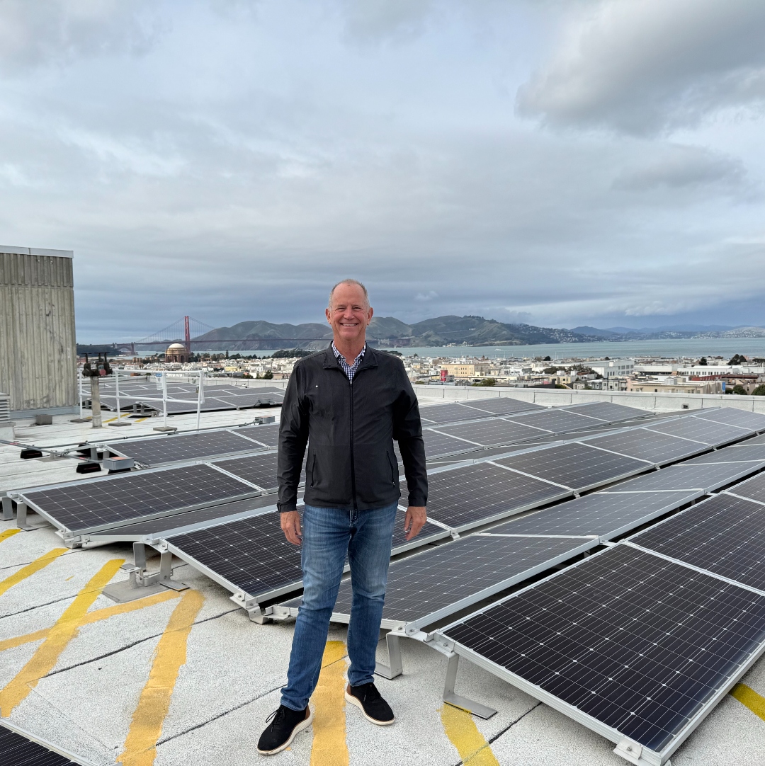 Lane Sharman on the rooftop solar array at 2001 Union Street, San Francisco — Golden Gate Bridge visible in the background